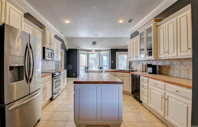 kitchen featuring backsplash, light tile patterned floors, tile counters, a kitchen island, and stainless steel appliances