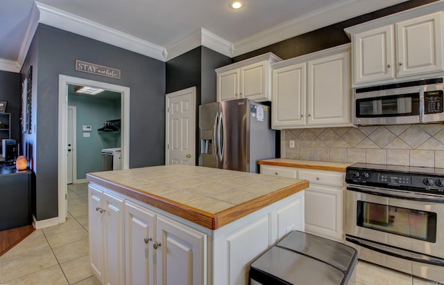 kitchen with white cabinetry, light tile patterned floors, washer and dryer, and appliances with stainless steel finishes