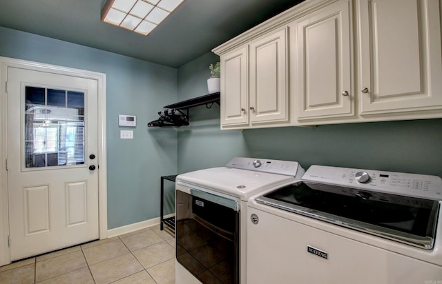 laundry room featuring cabinets, light tile patterned floors, and washing machine and dryer