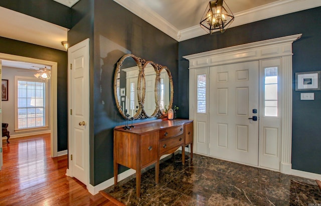 entrance foyer with ceiling fan with notable chandelier and crown molding