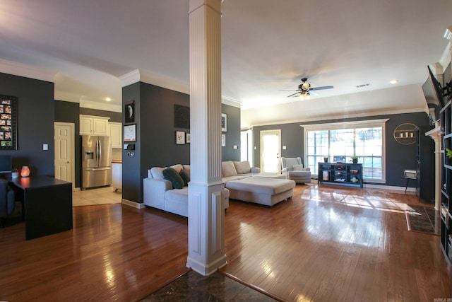 living room featuring decorative columns, ceiling fan, crown molding, and wood-type flooring