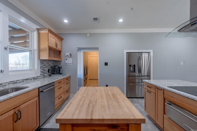 kitchen featuring butcher block countertops, a center island, ornamental molding, and appliances with stainless steel finishes