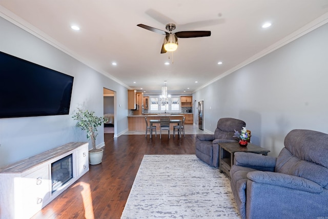 living room featuring dark hardwood / wood-style flooring, ceiling fan with notable chandelier, and ornamental molding