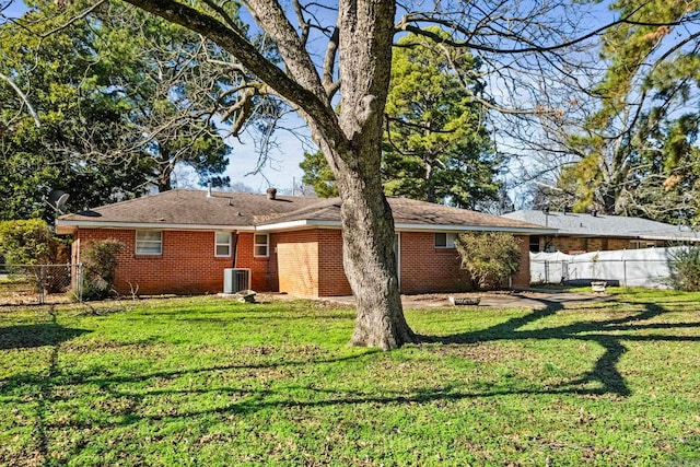 back of property featuring central AC unit and a lawn