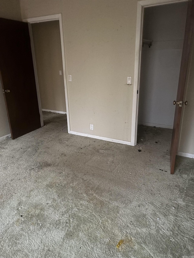 unfurnished bedroom with a walk in closet, a closet, and carpet floors