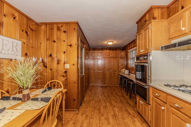 kitchen featuring black double oven, light hardwood / wood-style flooring, tasteful backsplash, and white gas cooktop