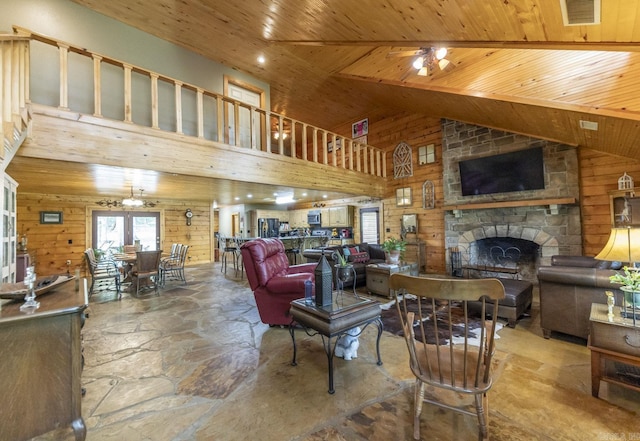 living room with ceiling fan, high vaulted ceiling, wooden walls, a fireplace, and wood ceiling