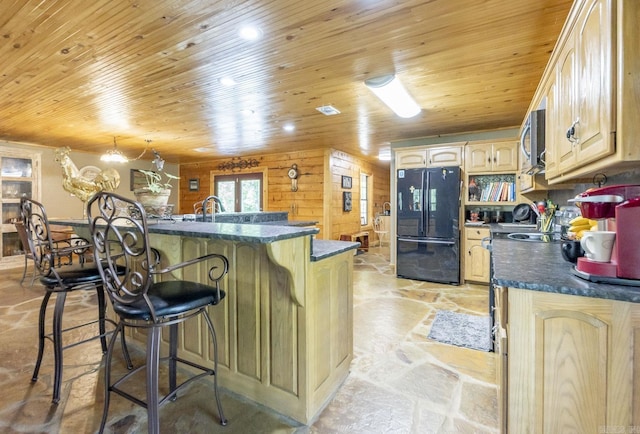 kitchen featuring wood walls, black refrigerator, wooden ceiling, and light brown cabinets