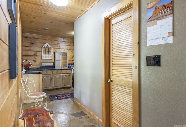 corridor featuring wooden walls, sink, and wood ceiling