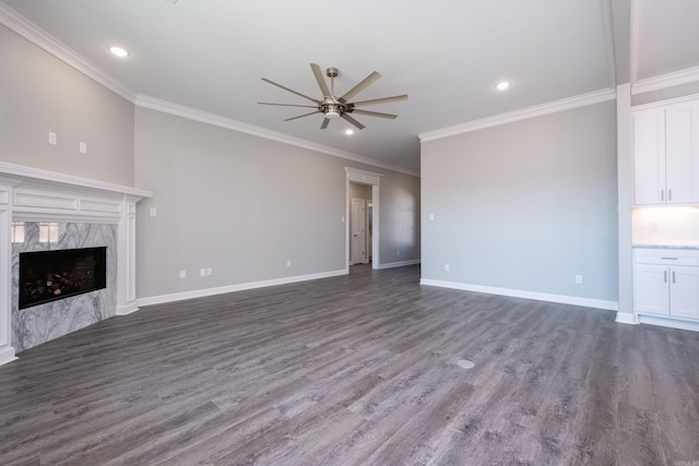 unfurnished living room featuring ceiling fan, a premium fireplace, dark wood-type flooring, and ornamental molding