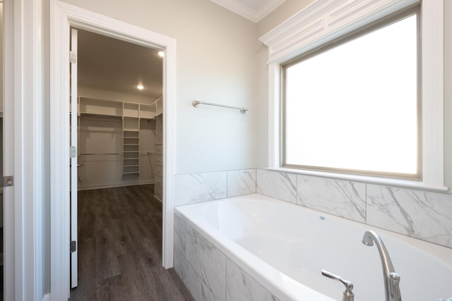 bathroom with wood-type flooring, crown molding, and tiled bath