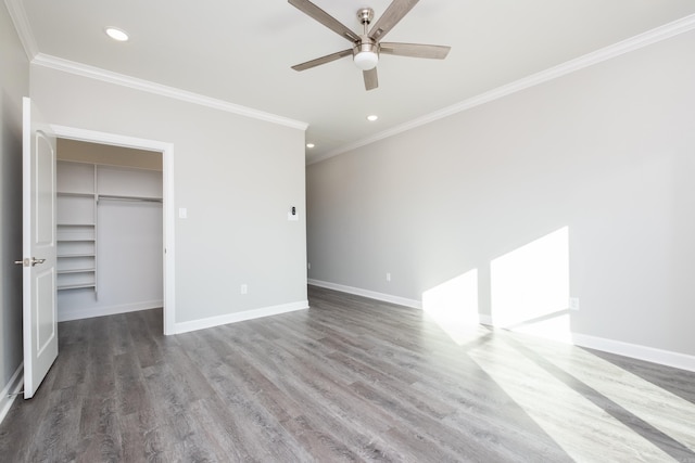 unfurnished bedroom featuring a walk in closet, dark hardwood / wood-style floors, ceiling fan, and ornamental molding