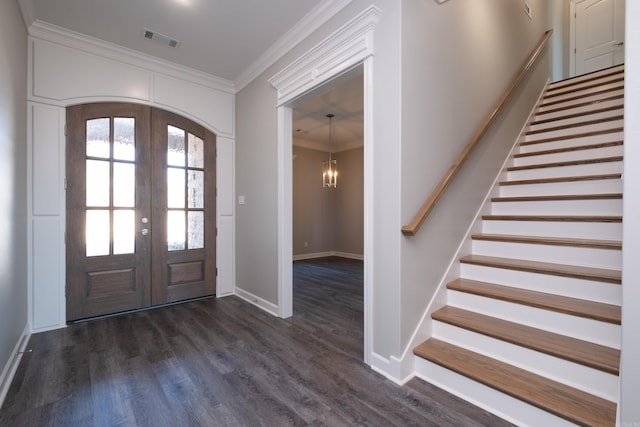 foyer entrance with dark hardwood / wood-style flooring, french doors, a notable chandelier, and ornamental molding