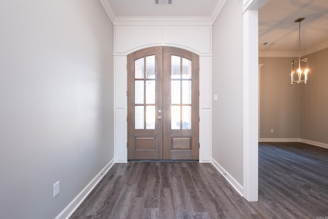 entrance foyer with a notable chandelier, dark wood-type flooring, crown molding, and french doors