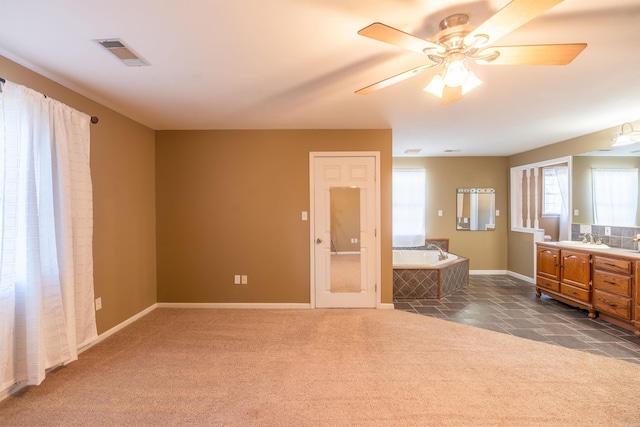 interior space featuring dark colored carpet, ceiling fan, and sink