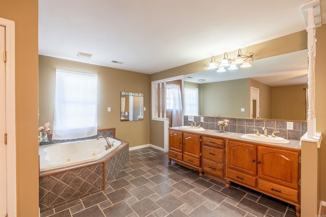 bathroom with decorative backsplash, vanity, and tiled tub