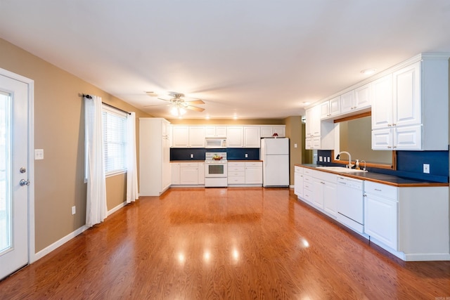 kitchen with white appliances, ceiling fan, sink, light hardwood / wood-style flooring, and white cabinets