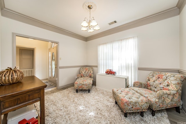 sitting room featuring hardwood / wood-style flooring, crown molding, and an inviting chandelier