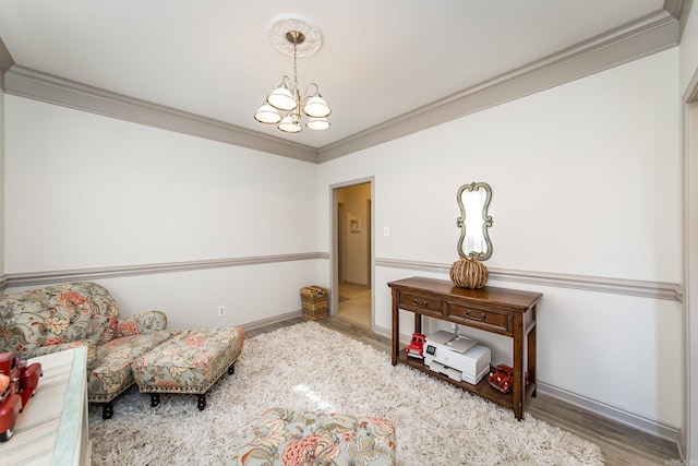 living area with hardwood / wood-style floors, an inviting chandelier, and ornamental molding