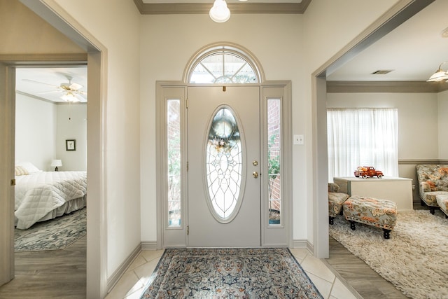 tiled entryway featuring ceiling fan and ornamental molding