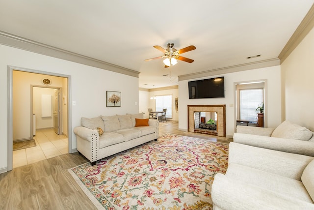 living room with ceiling fan, ornamental molding, a wealth of natural light, and light hardwood / wood-style flooring