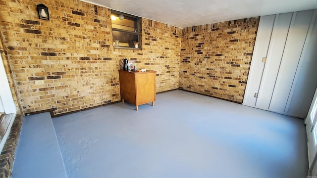 unfurnished room featuring concrete flooring and brick wall