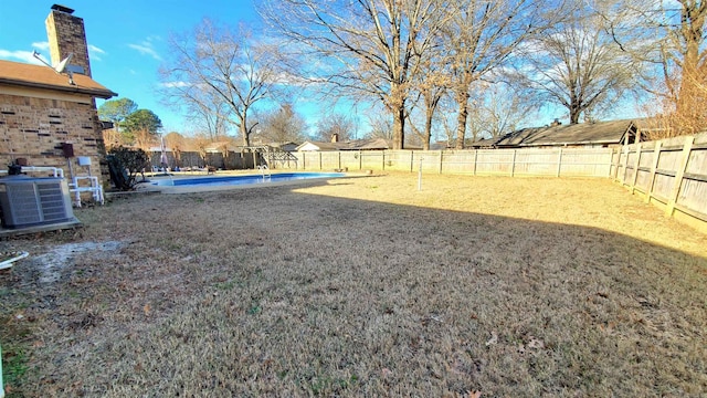 view of yard featuring central AC unit and a fenced in pool