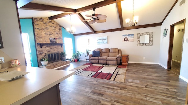 living room featuring vaulted ceiling with beams, a fireplace, dark hardwood / wood-style flooring, and ceiling fan with notable chandelier