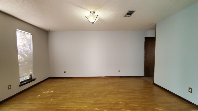 empty room featuring a textured ceiling and light hardwood / wood-style flooring