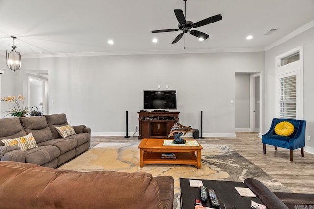 living room with ceiling fan with notable chandelier, light wood-type flooring, and crown molding