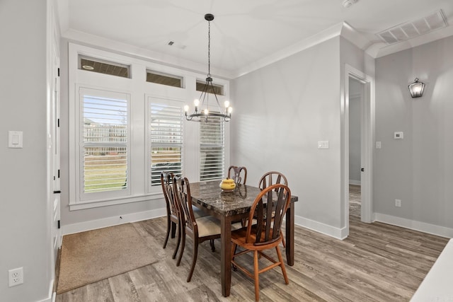 dining room with crown molding, hardwood / wood-style floors, and an inviting chandelier