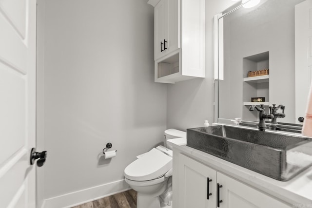 bathroom with wood-type flooring, vanity, and toilet