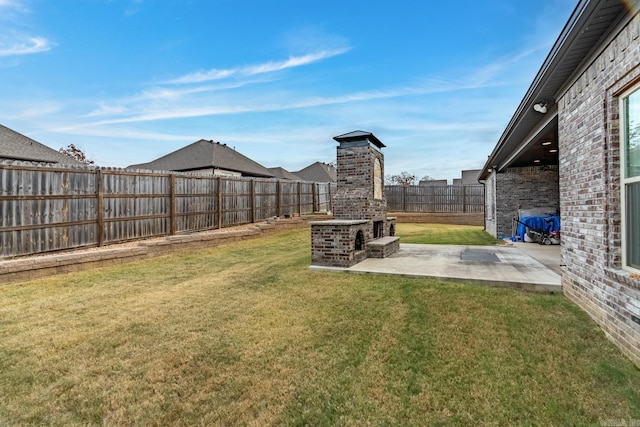 view of yard featuring a patio and an outdoor brick fireplace