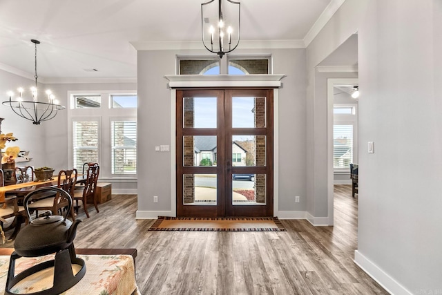 foyer entrance featuring french doors, hardwood / wood-style flooring, ornamental molding, and a notable chandelier