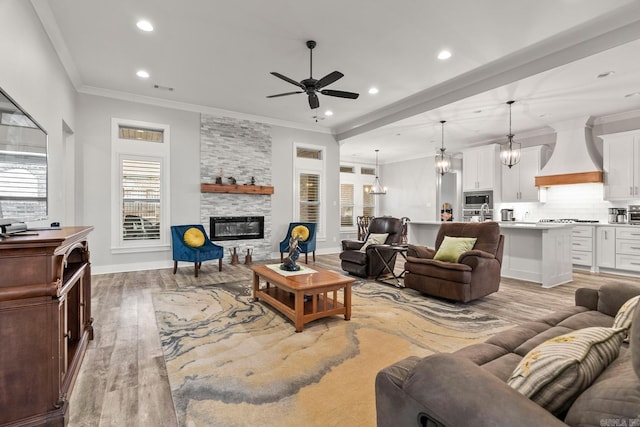 living room with light hardwood / wood-style floors, a stone fireplace, ceiling fan, and crown molding