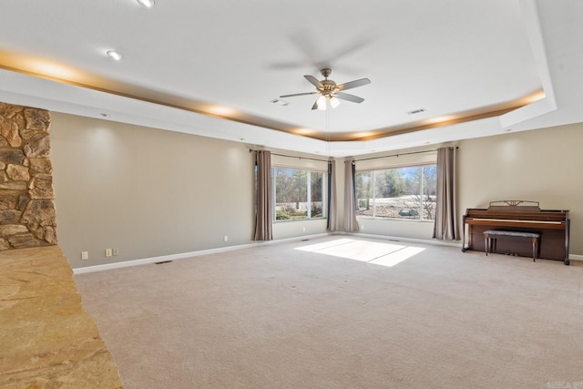 unfurnished living room featuring light carpet, a tray ceiling, and ceiling fan