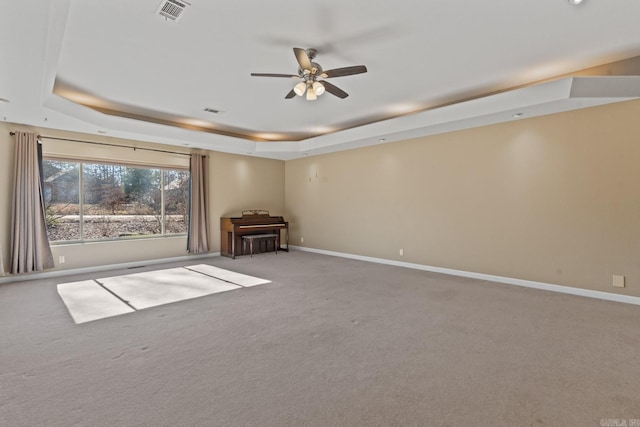 unfurnished living room featuring ceiling fan, a raised ceiling, and light colored carpet