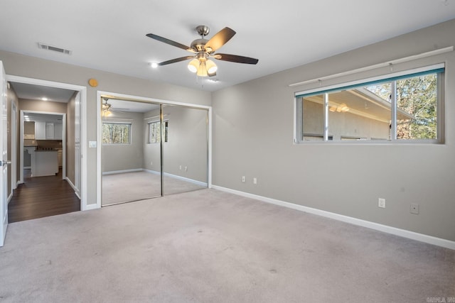 unfurnished bedroom with ceiling fan, light carpet, and a closet