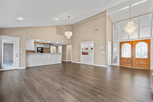 unfurnished living room with dark hardwood / wood-style flooring, french doors, a high ceiling, and a chandelier