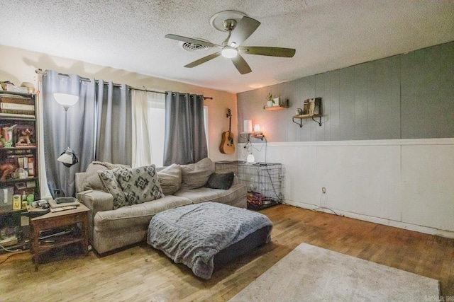 living room featuring hardwood / wood-style flooring, ceiling fan, and a textured ceiling