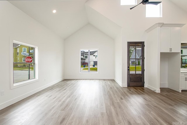 unfurnished living room with light hardwood / wood-style floors, high vaulted ceiling, and ceiling fan