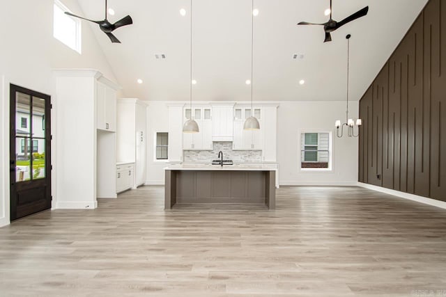 kitchen featuring a center island with sink, high vaulted ceiling, hanging light fixtures, and a healthy amount of sunlight