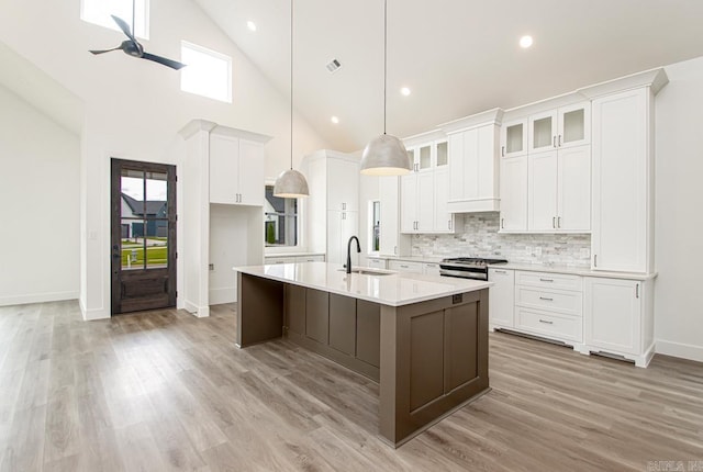 kitchen featuring white cabinetry, ceiling fan, sink, hanging light fixtures, and a center island with sink