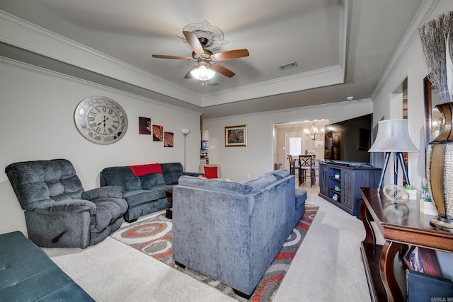 living room featuring a tray ceiling, carpet floors, and ceiling fan with notable chandelier