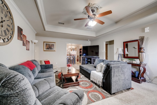 carpeted living room with a raised ceiling, crown molding, and ceiling fan with notable chandelier