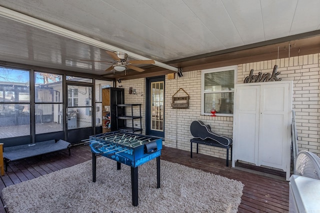 game room with ceiling fan, dark wood-type flooring, and brick wall