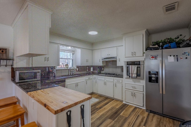 kitchen with white cabinets, sink, kitchen peninsula, and stainless steel appliances