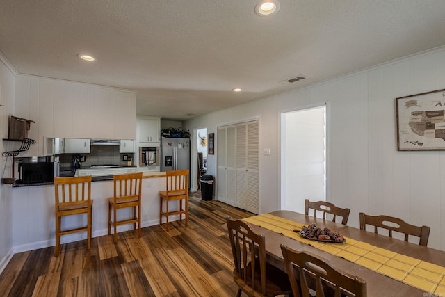 dining area featuring dark hardwood / wood-style flooring, a textured ceiling, and ornamental molding