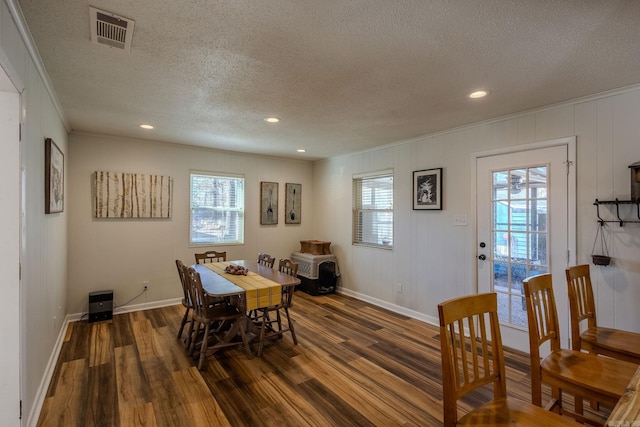 dining room with dark hardwood / wood-style flooring, a textured ceiling, and a wealth of natural light