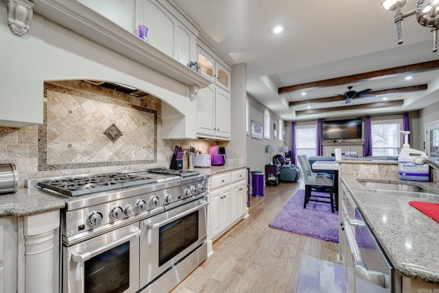 kitchen featuring appliances with stainless steel finishes, light stone counters, white cabinetry, and sink